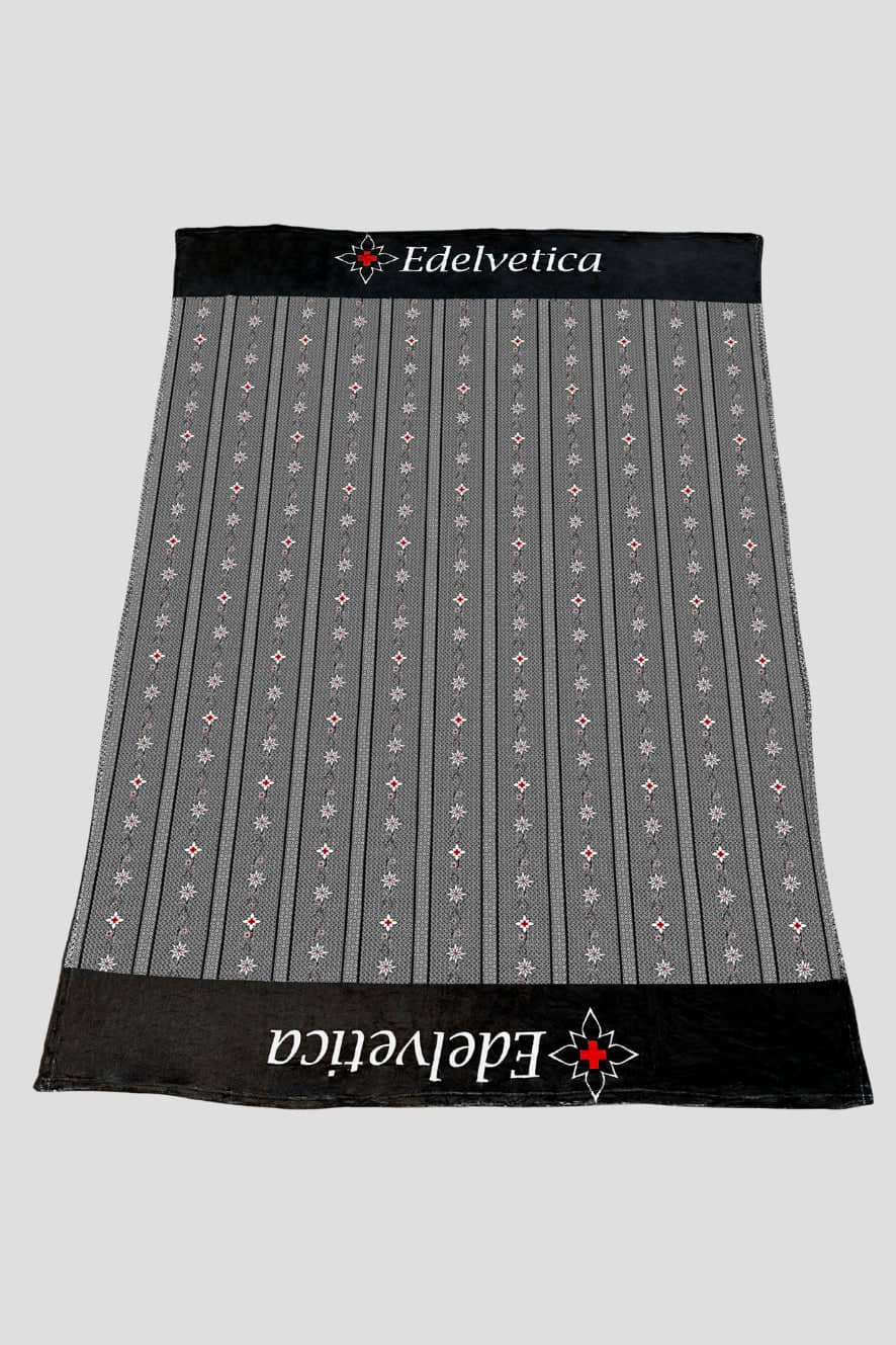 Edelvetica Edelweiss Kuscheldecke, eine weiche und gemütliche Decke, perfekt für entspannende Momente. Die Decke zeigt ein ansprechendes Edelweiss-Muster, das Wärme und Schweizer Charme in jeden Raum bringt. Ideal für kühle Abende oder als stilvolles Wohnaccessoire.