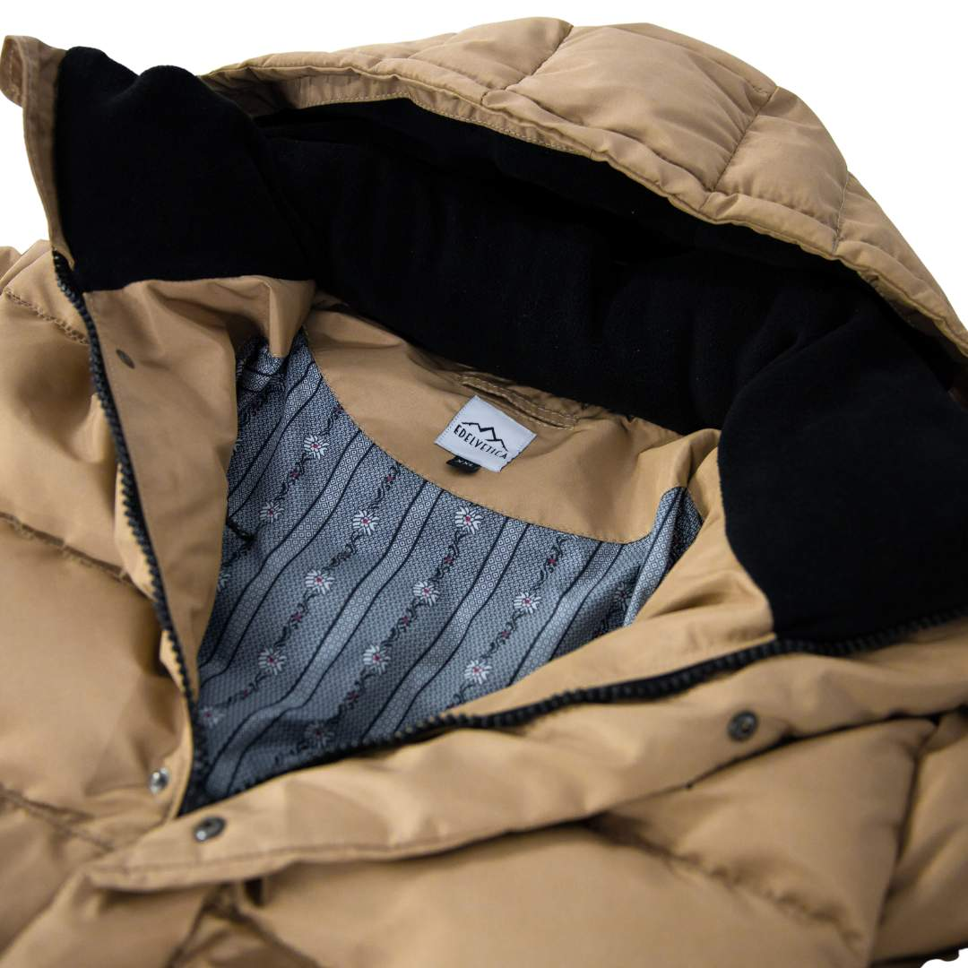 Damen Winterjacke von Edelvetica, handgefertigt für höchste Qualität. Diese stilvolle Jacke zeichnet sich durch ein einzigartiges Edelweiss-Muster auf der Innenseite aus, das traditionelle Schweizer Elemente mit modernem Design verbindet. Die Jacke verbindet Funktionalität mit einem stilvollen Design, ideal für den modischen Auftritt in der Winterlandschaft.